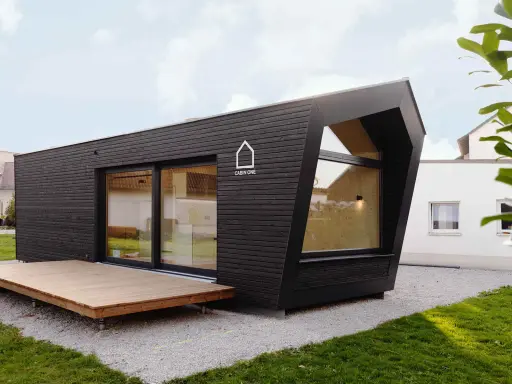 Modernes, dunkles Cabin House mit Holzterrasse und großem Fenster. Ein stilvolles Zuhause für minimalistisches Wohnen.