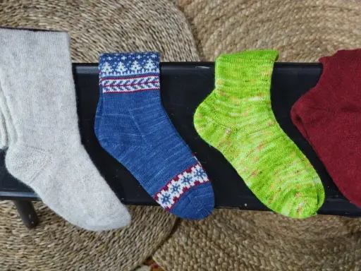 Fyra par handstickade sockor i olika färger och mönster. Perfekt för att sticka enkla sockor till barn.