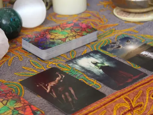 Tarot dzienny ryby: karty z mistycznymi obrazami, kryształ, kule i ozdobny obrus tworzą atmosferę wróżenia.