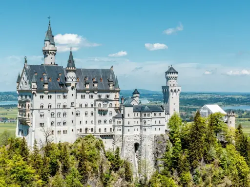 Märchenschloss Neuschwanstein, ein Meisterwerk romantischer Architektur, thront auf einem Felsen über einer malerischen Landschaft.