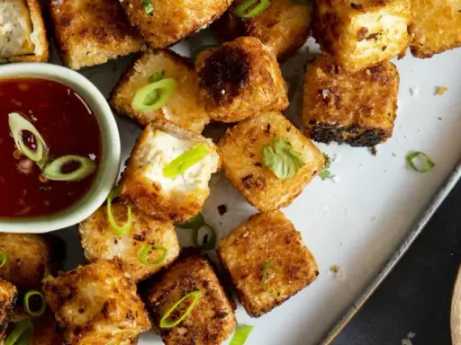 Krispiga, gyllene tofu-bitar serveras med en söt chilisås. Ett perfekt tofu recept för en snabb och god måltid.