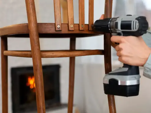 Persona repara una silla de madera con taladro. Un tornillo pasado de rosca dificulta la tarea.