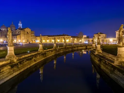 Prato della Valle di notte, un'idea di cosa vedere a Padova in un giorno. Statue e riflessi sull'acqua creano un'atmosfera magica.
