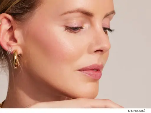 Profil d'une femme avec une peau éclatante, des boucles d'oreilles dorées et un maquillage subtil.