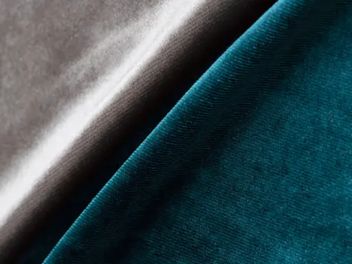 Tessuto in velluto a coste blu petrolio e grigio tortora, che mostra la morbidezza e la lucentezza di questo acetato che tessuto è.