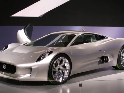 Silberner Jaguar C-X75 mit Flügeltür, der auf einer Messe ausgestellt wird.