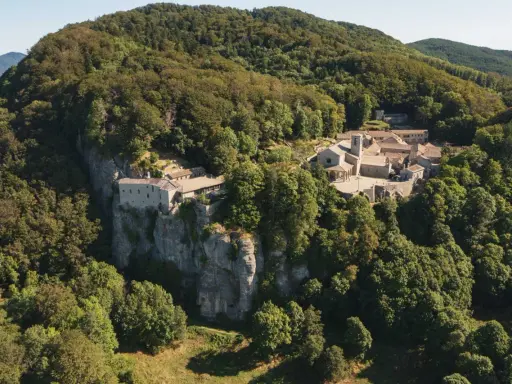 Il Santuario della Verna, incastonato tra i boschi, si erge maestoso su uno sperone roccioso. Un luogo di pace e spiritualità, meta di pellegrinaggi da Rimini e oltre.