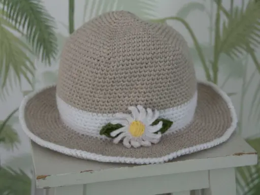 En virkad solhatt för barn, beige med vit kant och en söt blomdekor. Perfekt för soliga dagar!