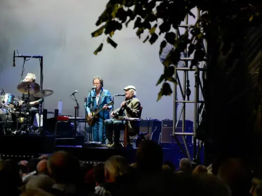 Alice Eva Larsen och hennes band uppträder på scenen. En trummis, en gitarrist i blå kostym och en sittande gitarrist med keps.