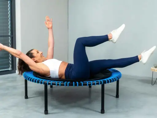 Frau macht ein intensives Workout auf einem Trampolin. Sie trainiert ihren Bauch, eine Übung, die man auch bei Tabata machen kann.