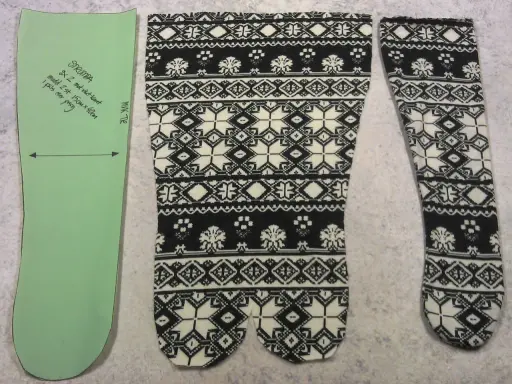 Mönster för att sy strumpor med nordiskt mönster i svart och vitt. En färdig strumpa ligger bredvid.