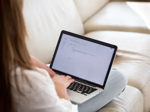 Kobieta pisze maila na laptopie, podkreślając ważne fragmenty tekstu.