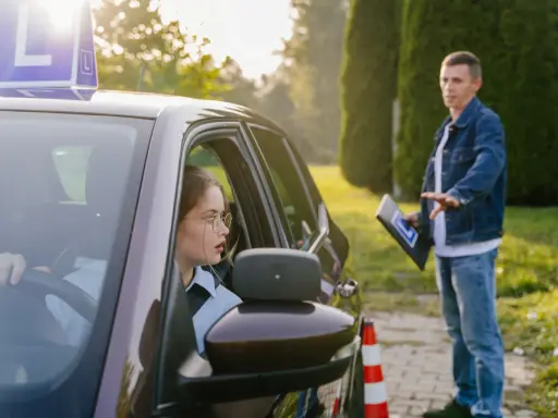 Młoda kobieta w okularach uczy się jeździć, a instruktor pokazuje jej, ile ważny jest kurs prawa jazdy.