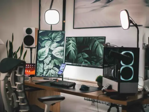 Escritorio moderno con doble monitor, PC con luces RGB, altavoces y plantas. Ideas para tu habitación gamer.