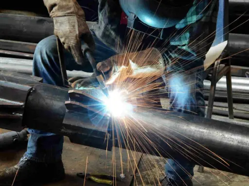 Un saldatore crea un legame forte, il vero significato del welding. Scintille luminose illuminano il metallo.