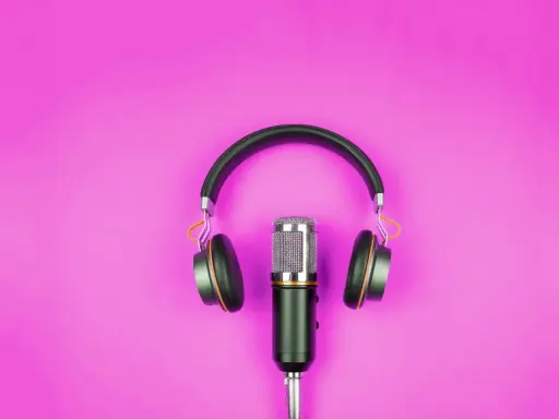 Microfono e cuffie su sfondo rosa, pronti per l'interpretariato di conferenza.