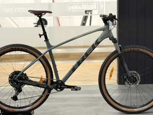Szary rower górski Trek Marlin 6 z brązowymi oponami Maxxis, gotowy na przygodę.