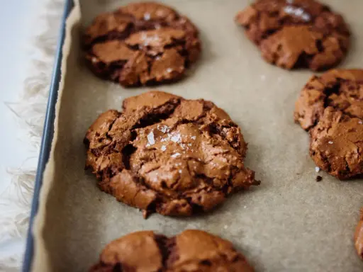 Saftige schoko cookies mit Meersalzflocken auf Backpapier, bereit zum Genießen.