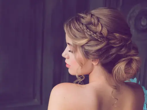 Elegante Frisur für Hochzeitsgäste: Ein kunstvoller Dutt mit geflochtenen Akzenten und zarten Locken.