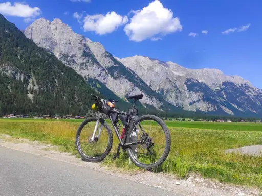 Rennrad für einen Alpencross, bereit für die Berge. Gepäcktaschen sind montiert, die Alpenkulisse ist atemberaubend.
