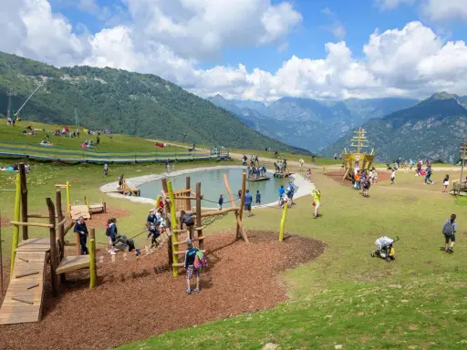 Un parco giochi in montagna con un laghetto, un galeone e tante famiglie che si divertono. Perfetto per le vacanze in montagna con bambini.