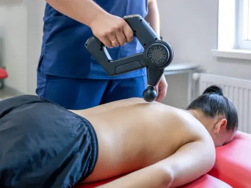 Fizjoterapeuta wykonuje masaż wibracyjny pleców. Choć zazwyczaj przynosi ulgę, warto pamiętać o potencjalnych skutkach ubocznych masażu wibracyjnego.