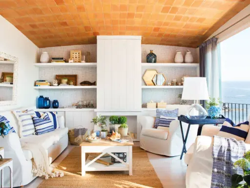 Salón con vistas al mar, decoración náutica y techo de tejas. Un espacio que evoca la sensación de estar en la playa en casa.