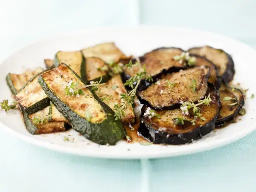 Gebratene Zucchini und Auberginen, italienisch gewürzt mit Kräutern, auf einem Teller.