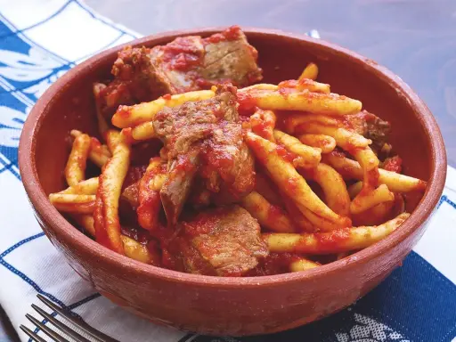 Piatto di pasta fresca con ragù di carne, un sapore autentico del cibo tipico calabrese in una ciotola di terracotta.