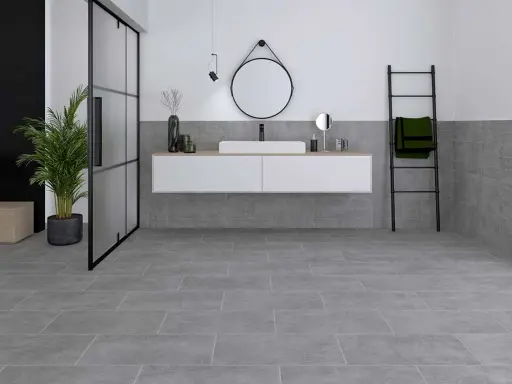 Modernes Badezimmer mit grauen Bodenfliesen und Wandfliesen, die das Ambiente von fliesen sanieren unterstreichen. Ein schwebendes Waschbecken und eine Glasdusche runden das Bild ab.