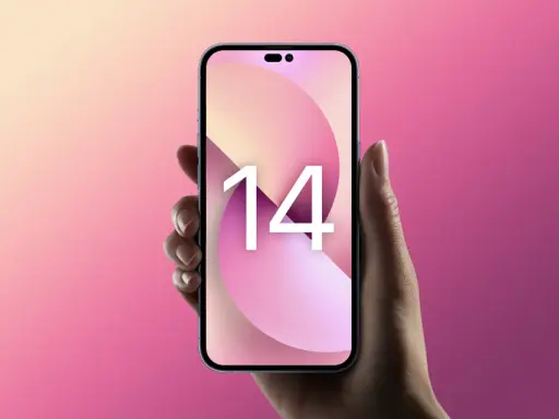 Dłoń trzyma różowy iPhone 14 z tapetą z cyfrą 14 na tle gradientu różu i beżu.