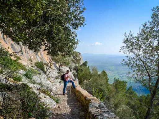 Mann mit Wanderstock und Rucksack genießt die Aussicht auf Mallorca. Ein toller Tag zum Wandern auf Mallorca!