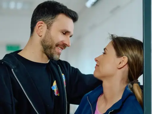 Uśmiechnięty mężczyzna patrzy na kobietę, która opiera się o ścianę. Może rozmawiają o tym, jak czytać mangę.