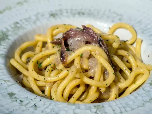 Un piatto di spaghetti con acciughe e prezzemolo, un'ottima idea per scoprire cosa mangiare a Padova.
