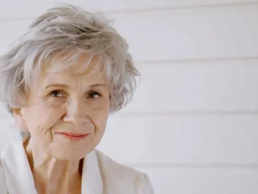 Ritratto di Alice Munro, con capelli grigi spettinati e un sorriso gentile.