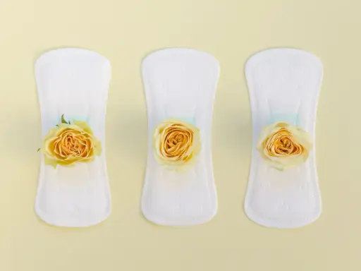 Tres compresas blancas con rosas amarillas, simbolizando un flujo amarillo antes de la regla.