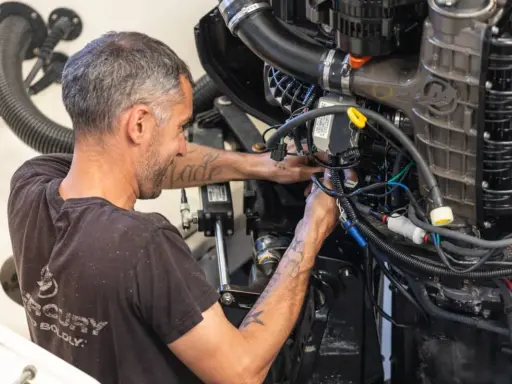 Un mécanicien s'affaire sur un moteur électrique, câbles et tuyaux visibles. Il sait comment tester un moteur électrique pour assurer son bon fonctionnement.