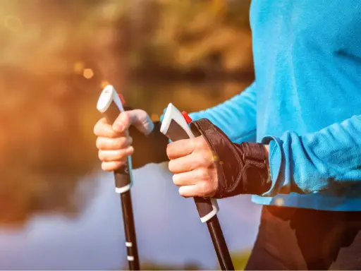 Radość z aktywnego życia po przeszczepie nerki. Dłonie trzymające kije do nordic walking na tle jesiennego krajobrazu.