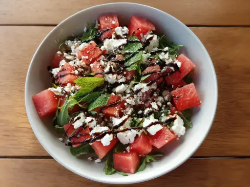 En uppfriskande sallad med tärnad vattenmelon, smulad fetaost och färsk basilika, ringlad med balsamvinäger.