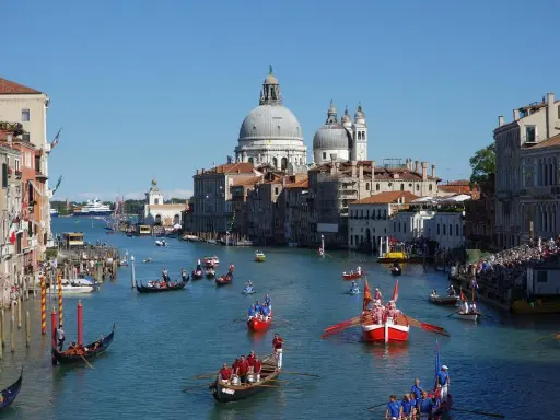 La Regata Storica anime le eaux de Venise, avec des gondoles et des bateaux traditionnels en compétition, sous le regard de la basilique Santa Maria della Salute.