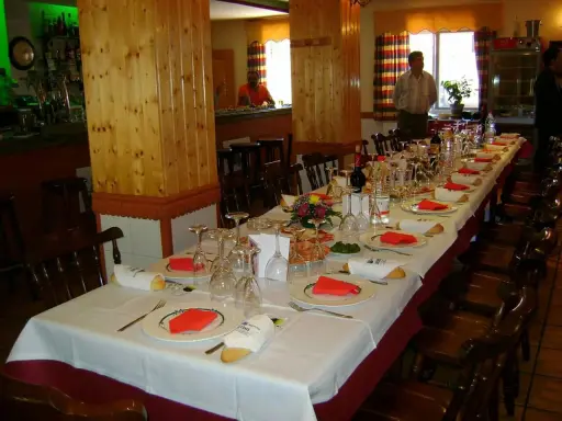 Mesa larga y elegante lista para comer en Riopar, con copas, platos y panecillos.