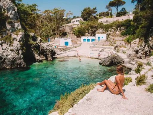 Una ragazza ammira la baia cristallina. Perfetto per decidere cosa fare stasera in Puglia: un tuffo rinfrescante!