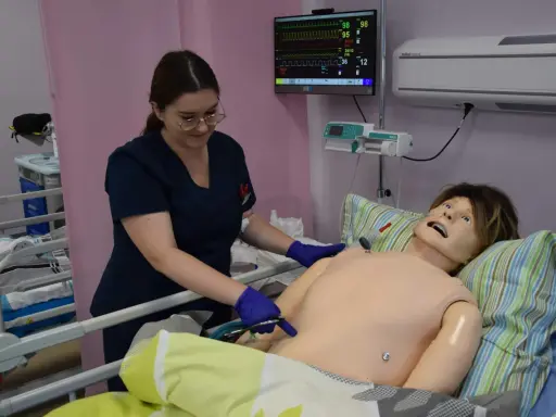 Studentka medycyny ćwiczy na fantomie, jak wyglądają studia medyczne. Monitor pokazuje parametry życiowe.