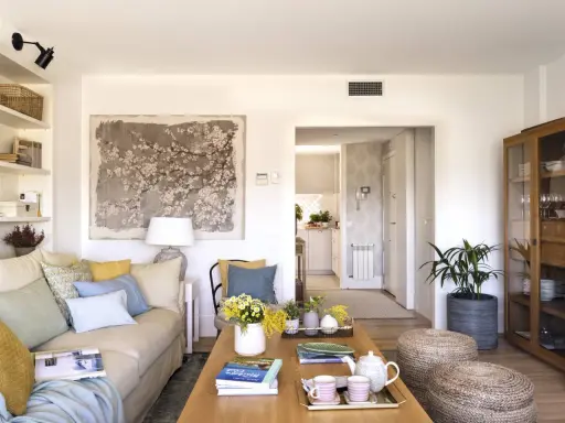 Ideas para decorar un salón moderno y elegante: sofá beige, mesa de centro de madera, arte floral, plantas y detalles acogedores.