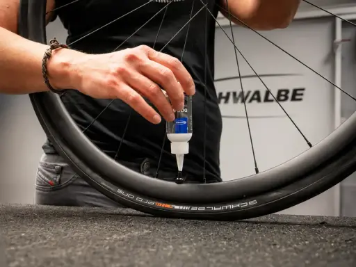 Eine Hand gibt Dichtmilch in den Fahrradschlauch eines Schwalbe Reifens.
