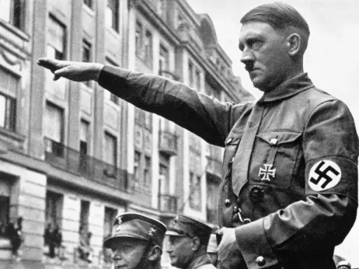 Adolf Hitler hebt den Arm zum Gruß. Seine Uniform zeigt das Hakenkreuz. Die Frage, wie kam Hitler an die Macht, beschäftigt Historiker bis heute.