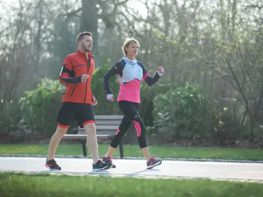 Ein Mann und eine Frau machen zügig **power walking** im Park.