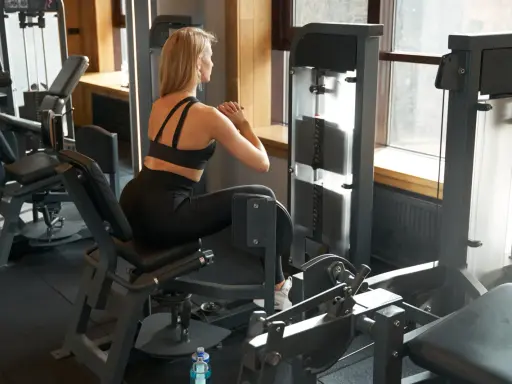 Frau trainiert im Fitnessstudio an einem Gerät für Bauch, Beine und Po.