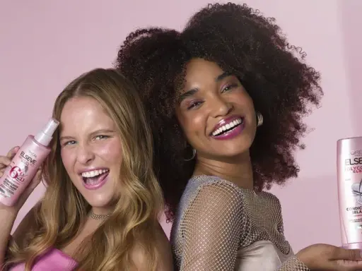 Dos mujeres sonríen, una con pelo liso y otra con pelo esponja, ambas sostienen productos Elseve para un brillo espectacular.