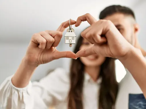 Un couple non marié célèbre son achat maison. Les mains forment un cœur autour de la clé, symbole de leur nouveau foyer, un nouveau départ après un décès.